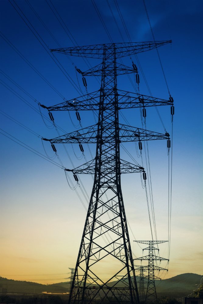 Transmission tower silhouetted against a blue dusk sky