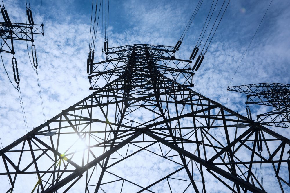 High-voltage transmission tower against a bright blue sky
