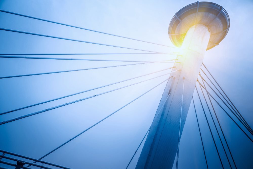 Modern cable-stayed tower lit by the sun against a blue sky